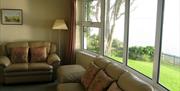 garden and sea view from the lounge. Also showing two leather sofas, florrlamp and footstool