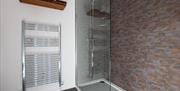 Image shows walk in shower area and large stainless steel towel radiator