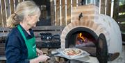 Tracey cooking pizza in her garden pizza oven