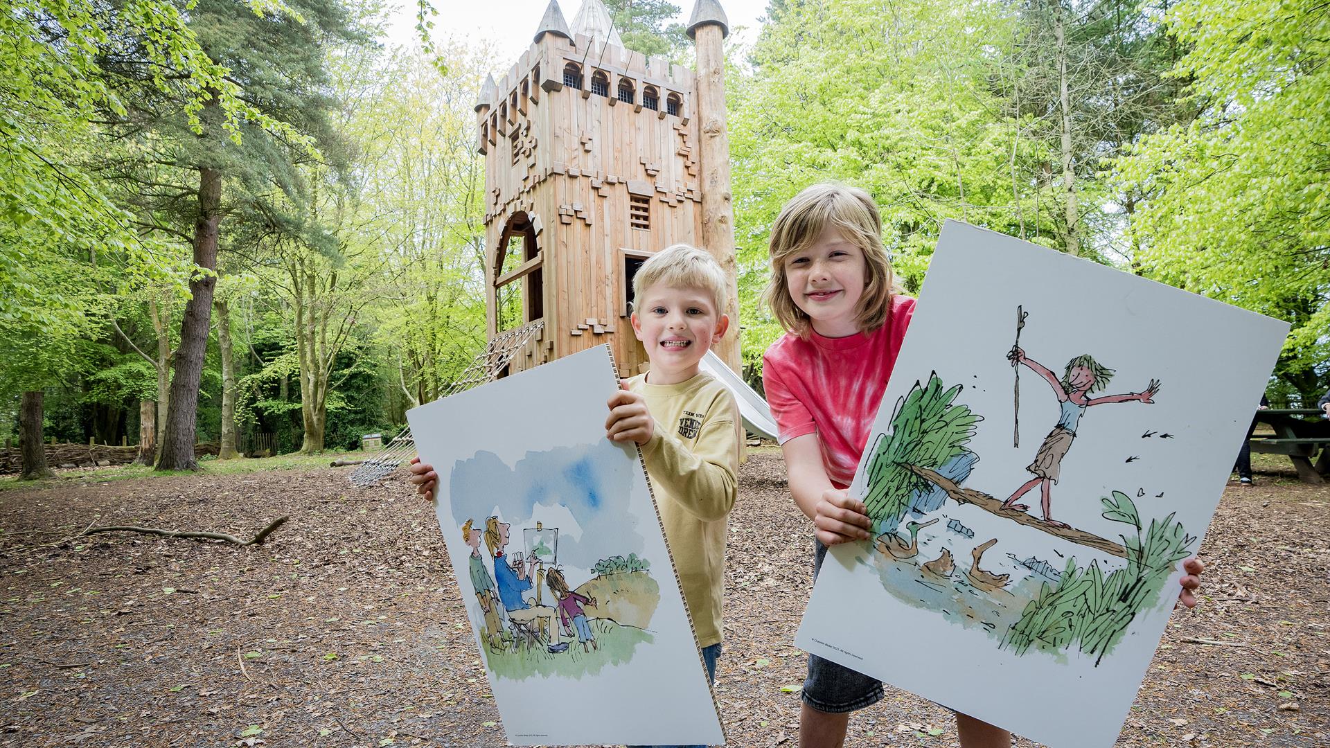 Two children holding poster boards of illustrations by Quentin Blake, in the grounds of WWT Castle Espie