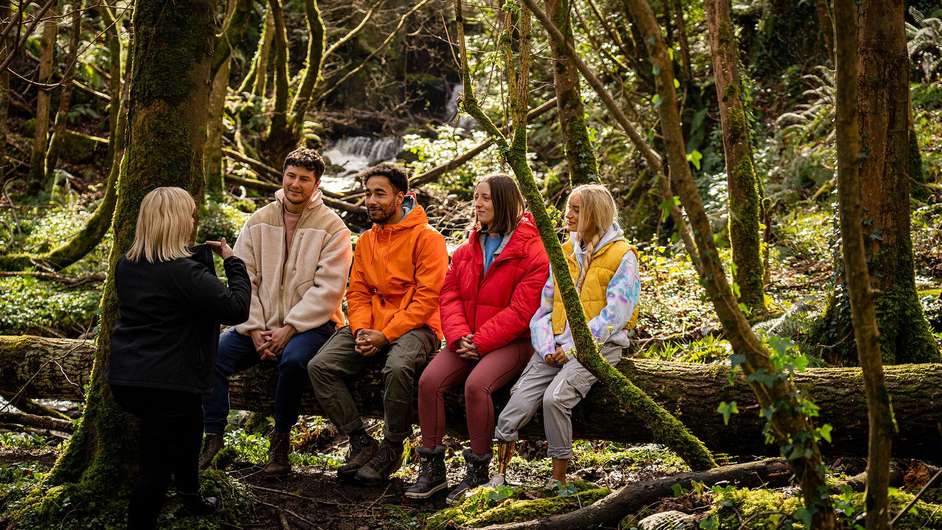 Group sitting on a tree listening to their guide as part of the Mussenden Unwind experience