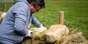 Man placing a heavy stone on a wall as part of the Mourne Dry Stone Wall Building experience