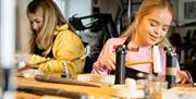 Two girls making jewellery as part of the workshop with Gobbins Crafts in Islandmagee