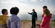 Guide Rodney at the top of Cavehill talking to the group with views of Belfast in the background as part of the Cavehill Walking Tours experience with