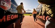 Girl with a hurl running out on the pitch from the tunnel alongside a man carrying a ball at Armagh GAA