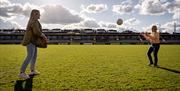 Two girls playing with a football on the pitch at Armagh GAA