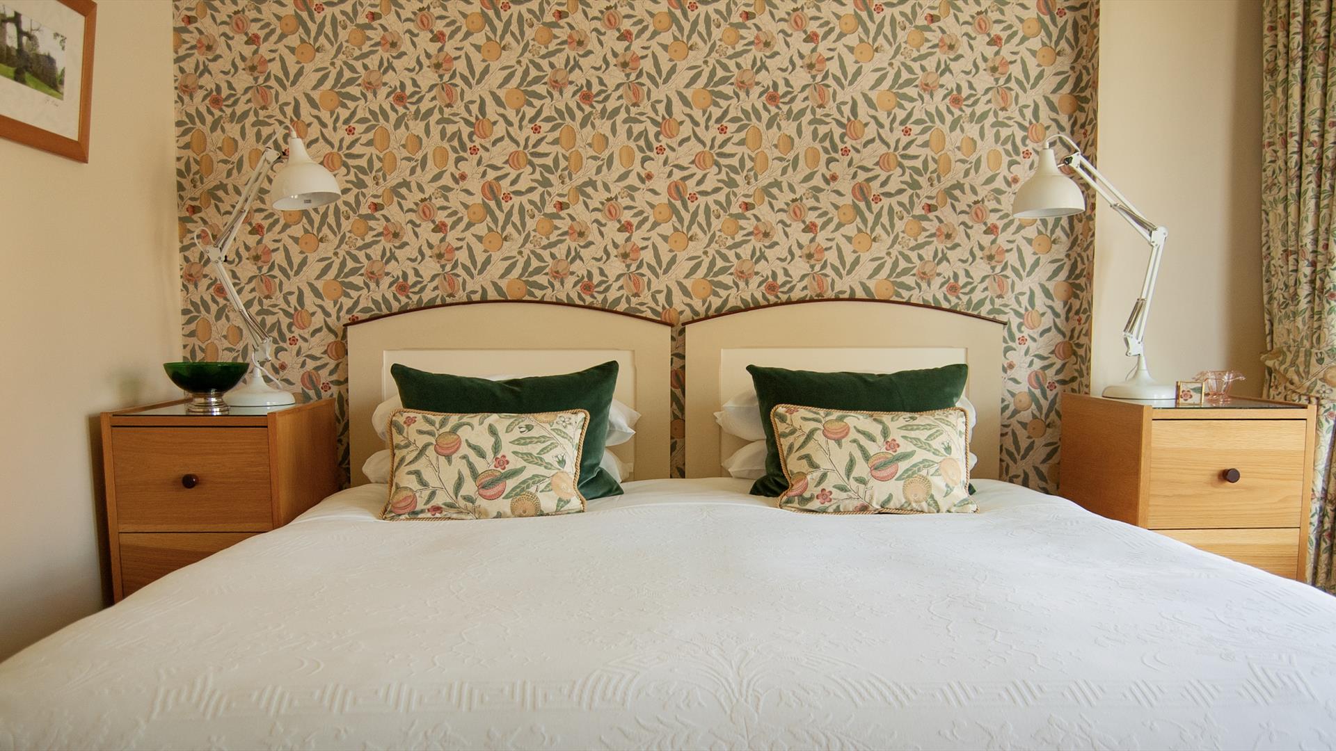 Image of a bed with patterned wall paper and matching cushions.