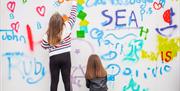 Kids having a go at the Sea Bangor Graffiti wall