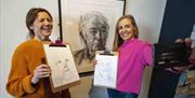 A couple of women take a selfie showing their attempts at sketching an image of Seamus Heaney