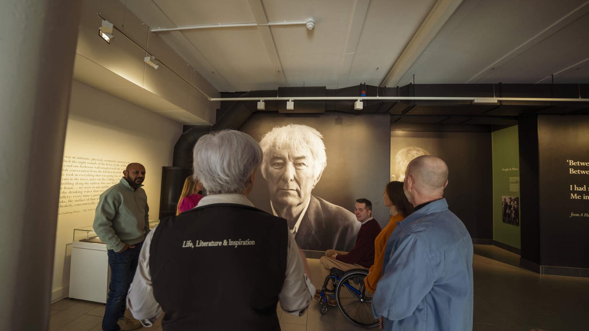 A photograph of Seamus Heaney is admired by a tour group