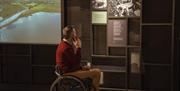 A man in a wheelchair listens to an audio tour of the Seamus Heaney HomePlace