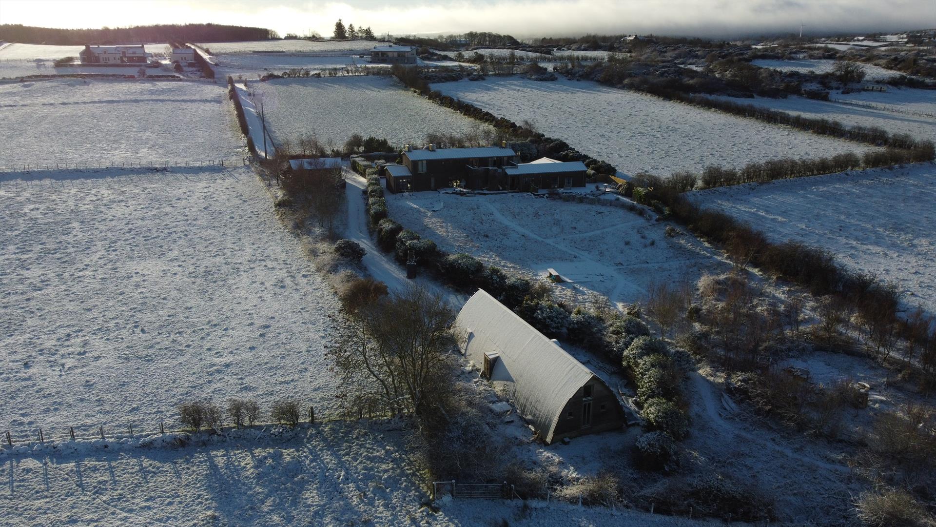 An aerial view of the studio on a Snowy winter day with the snow glistening on the curved roof.