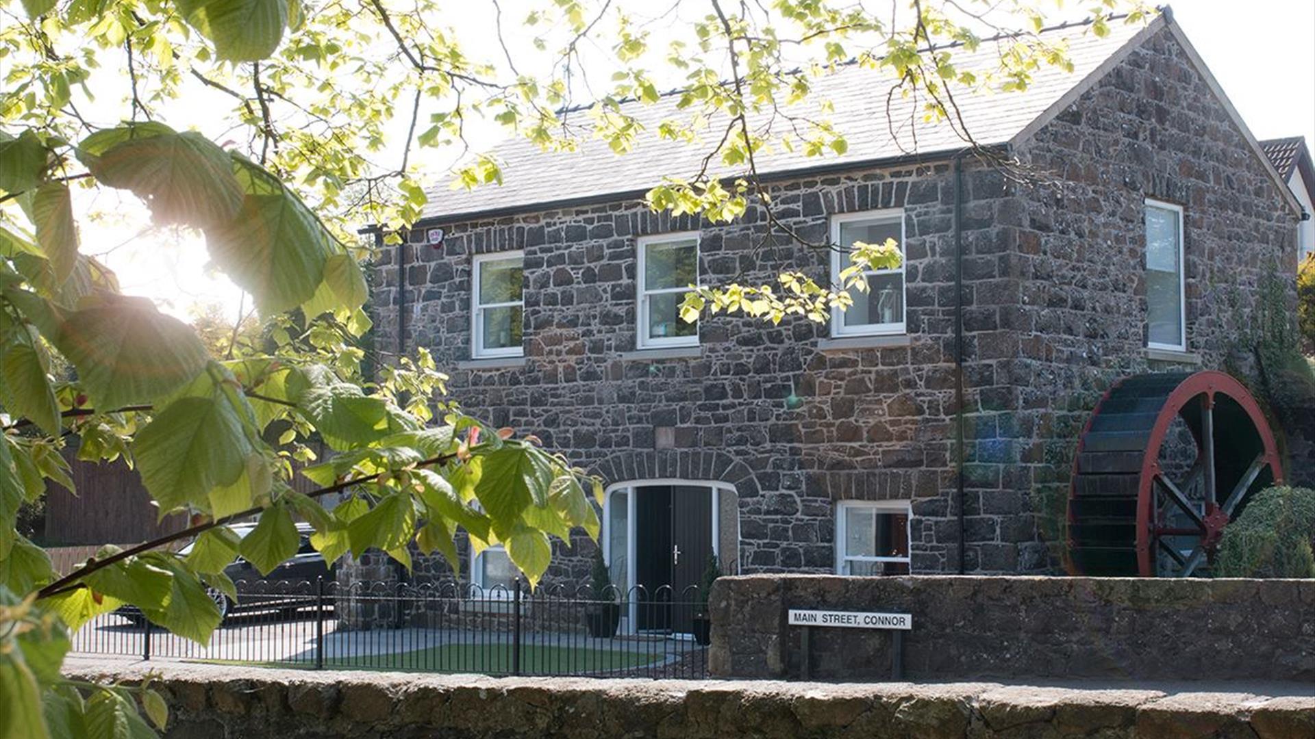 Stone Flax Mill restored self catering - black stone building with water wheel at side of house