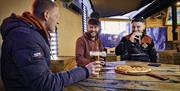 group of 3 males sharing pizza and drinking
