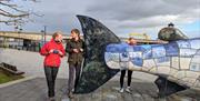 Visitors taking photographs at the Big Fish sculpture, Belfast Laganside.