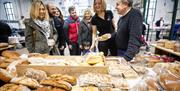 Visitors with tour guide St. George's Market at stall of baked home-made breads