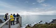 Group chats as they stand on a suspended viewing platform overlooking the Irish Sea