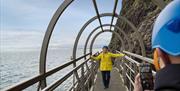 Woman poses for a photograph on the eye catching bridge at The Gobbins