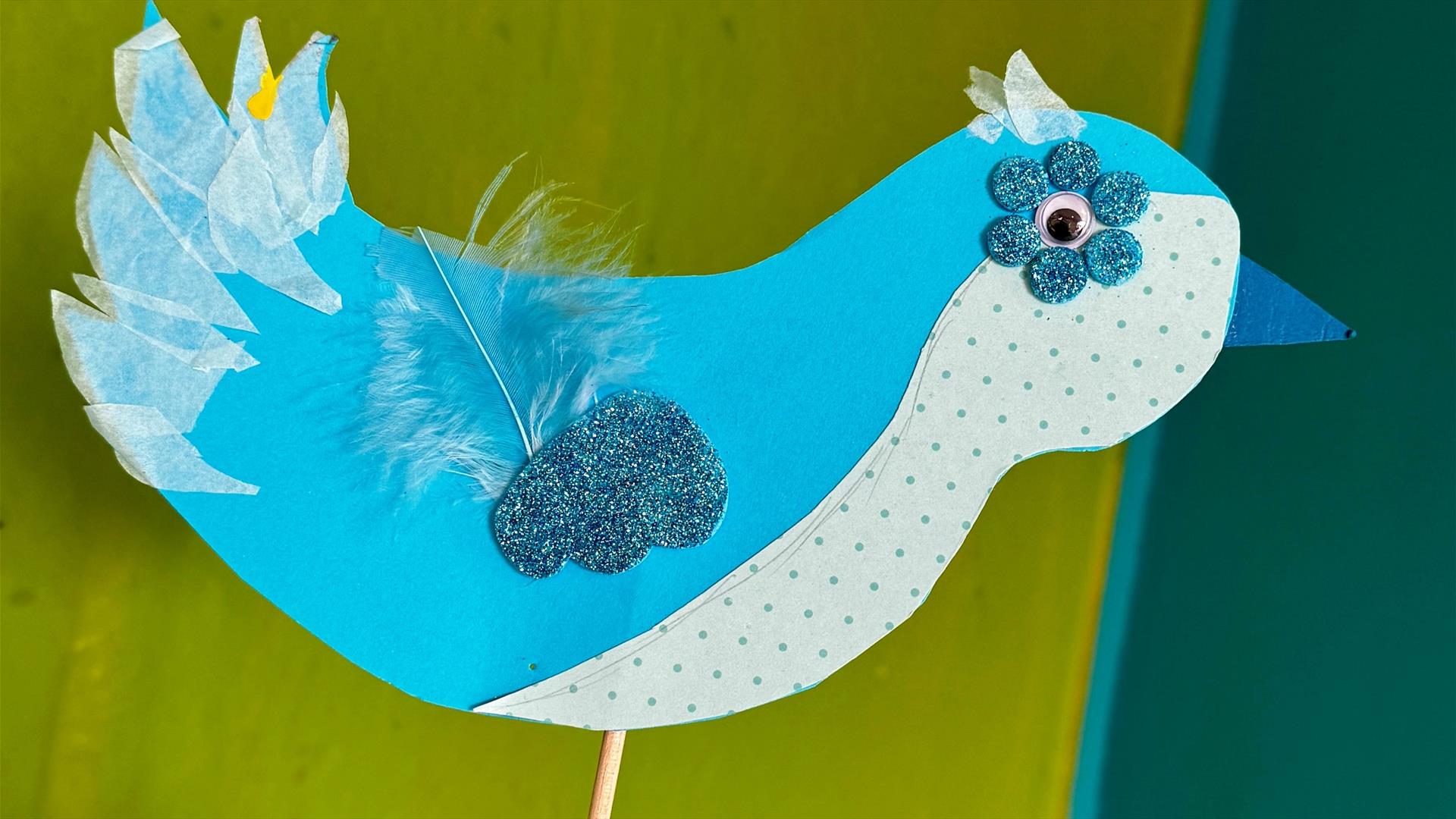 Collage bird made from card, tissue paper, feathers and other craft materials.