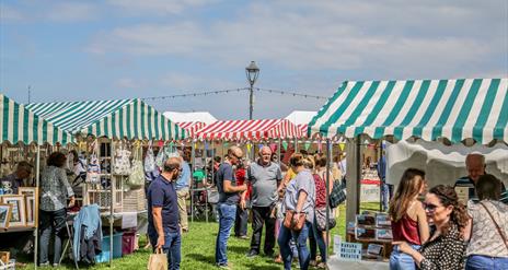 crowds of people browsing busy seaside market stalls