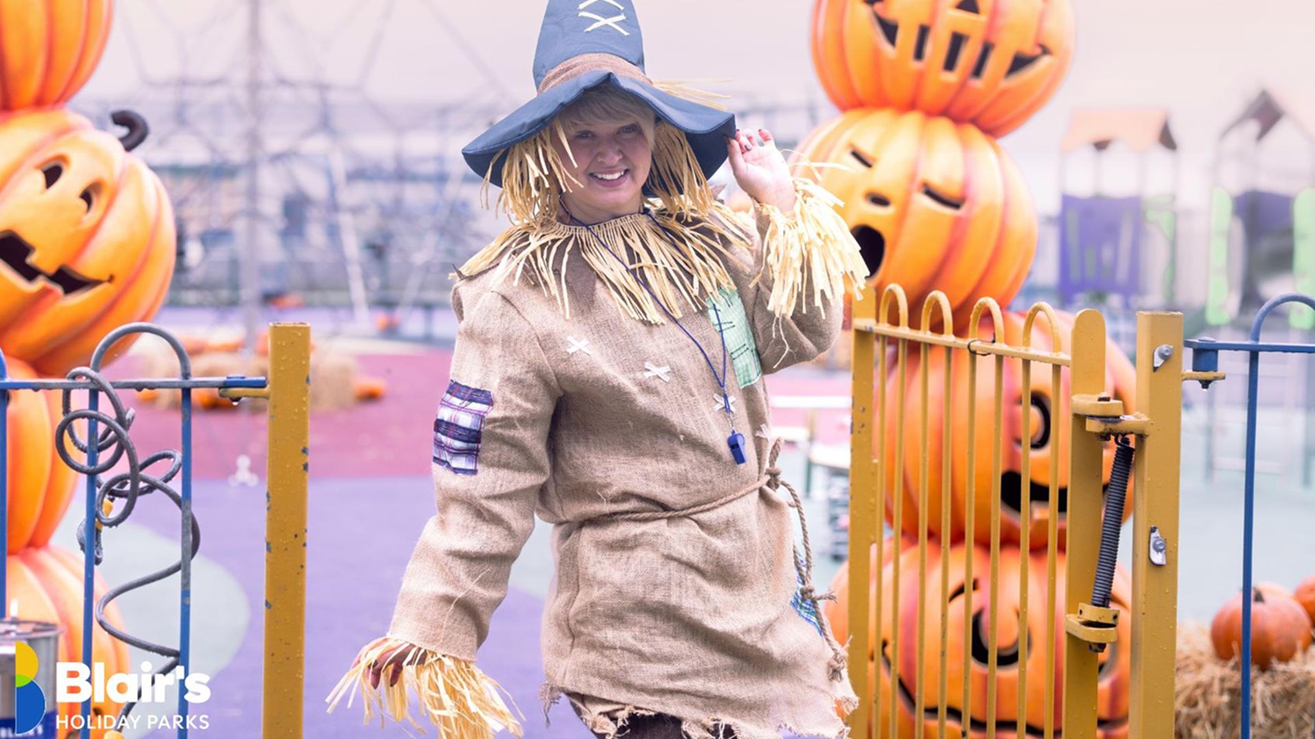 a person dressed as a scarecrow poses at Blair's Holiday Park, surrounded by pumpkin decorations a person dressed as a scarecrow poses at Blair's Holiday Park, surrounded by pumpkin decorations