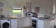 Image shows open plan kitchen with washing machine/dryer, oven and fridge/freezer.
