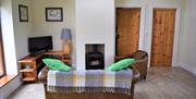 Image shows the living room with sofa, armchair and wood burning stove. Doors to bedroom and bathroom.