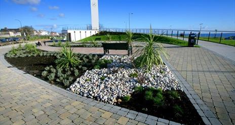 Planted border beside paving area with Carrickfergus Clock Tower to rear