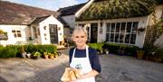 Tracey standing outside the front entrance of her home holding homemade soda bread