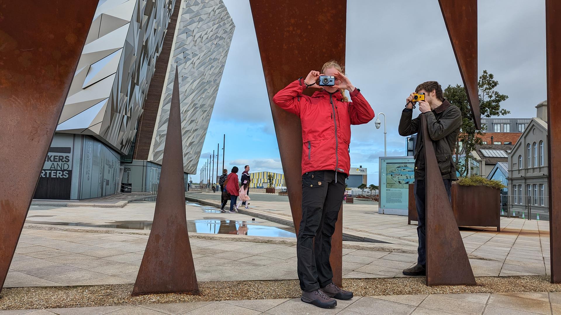 Two visitors taking pictures with Konica Pop cameras at the Titanic sign.