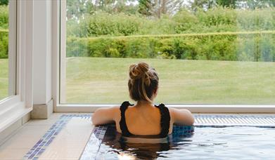 image of woman in pool looking out of large glass aspect window