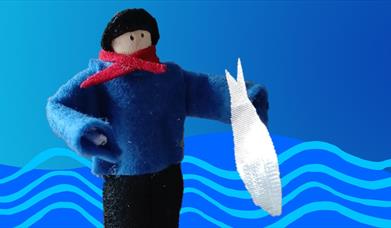 A peg doll dressed in felt clothes asa fisherman with black hat, blue gansey jumper and red necktie, holding a silver fabric fish.