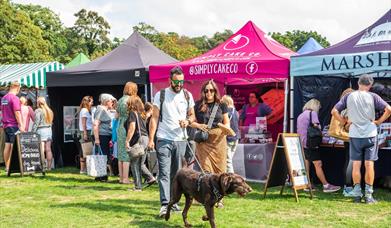 Two people and their dog in front of the food stalls at North Norfolk Food and Drink Festival
