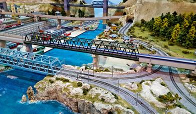 Model railway of a Japanese bullet train travelling across high speed rails from the city into the countryside.