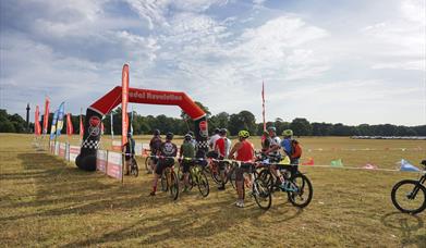 Cyclists at the finish line in Holkham Park on a summer's day.