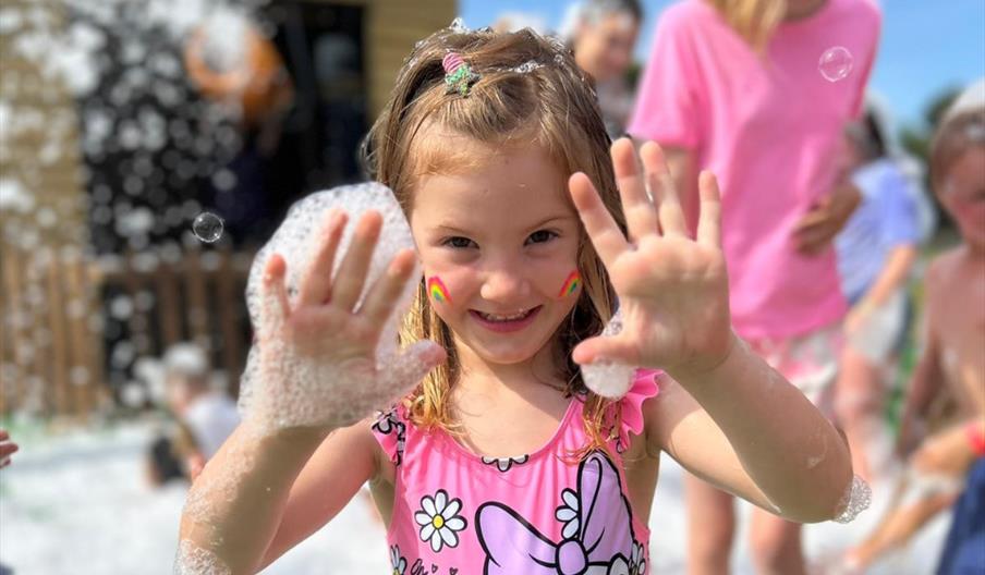 Child enjoying a foam party at Wroxham Barns