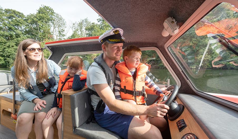 Dad steering a day boat in the Broads National Park