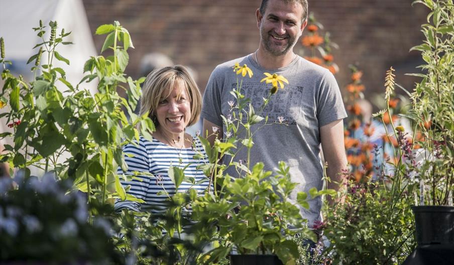 A white woman and man smiling in front of a Flower stand at Holkham Walled Garden