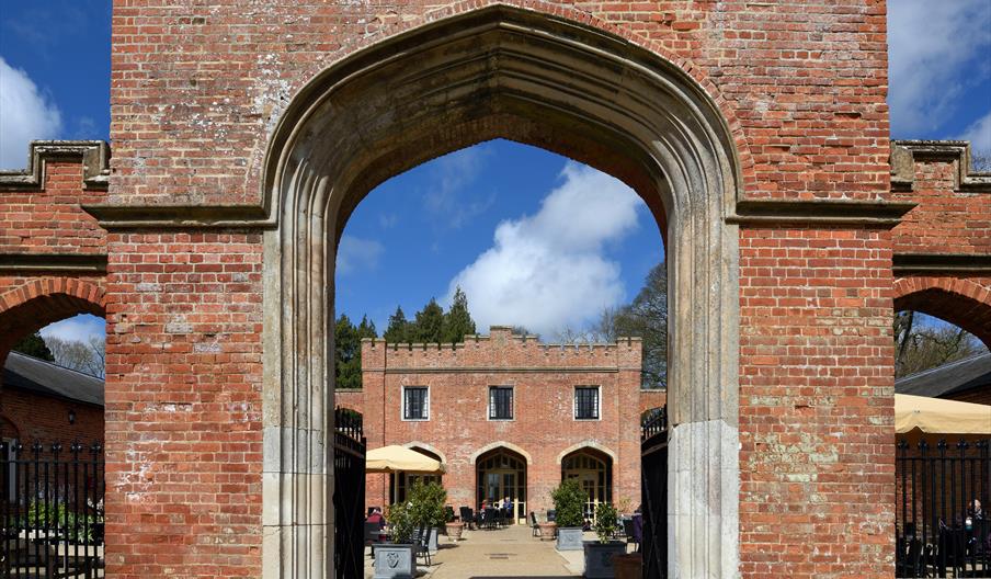 View through an archway to the courtyard with outside seating at Felbrigg Hall, Norfolk