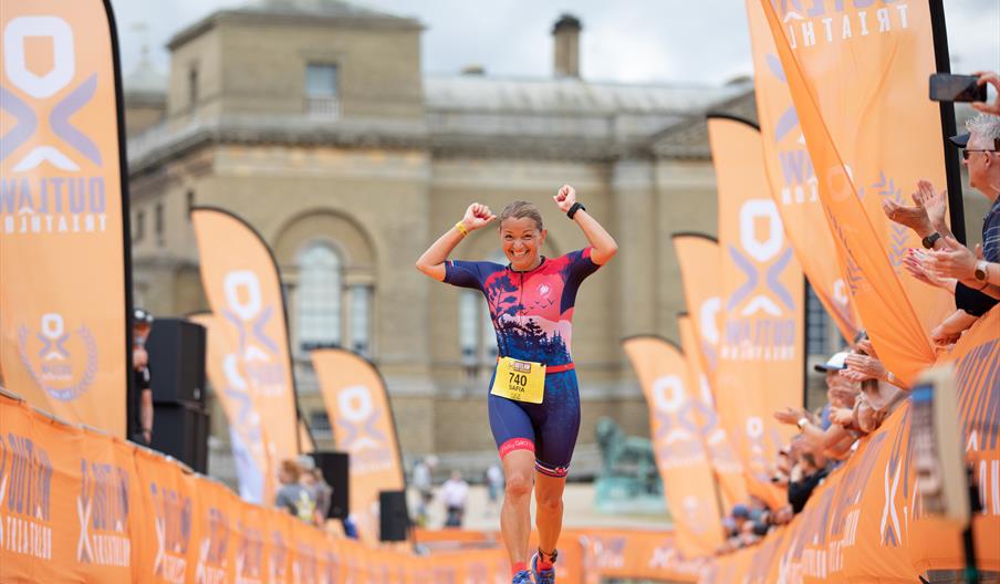 A runner on the orange finish line in front of Holkham Hall