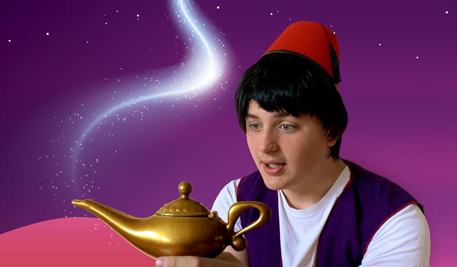 A young boy with black hair and wearing a red fez, Aladdin, holds a golden lamp
