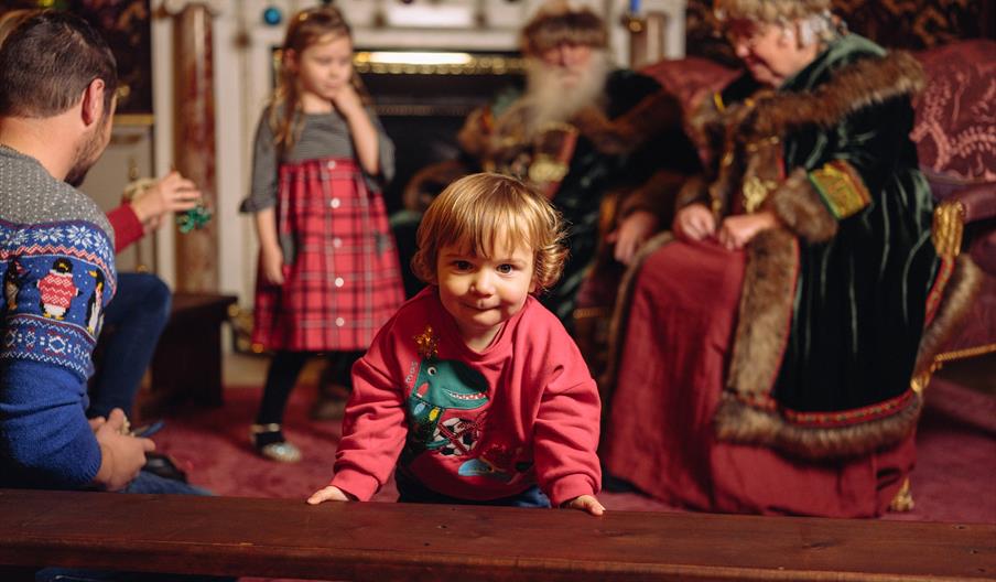 A child at Holkham Hall with Mother and Father Christmas