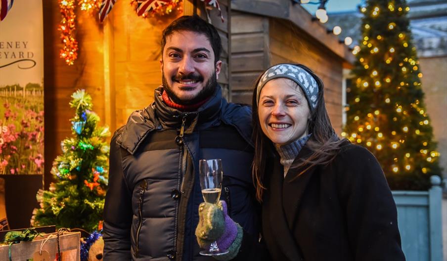 Two people smile as they enjoy Holkham Christmas Market in North Norfolk.