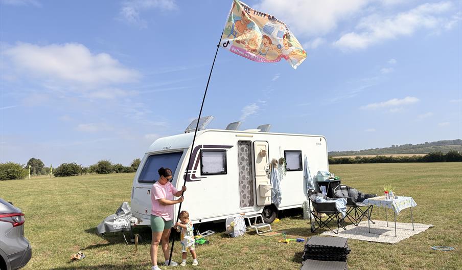 A mother and her child put  up a flag outside their caravan.