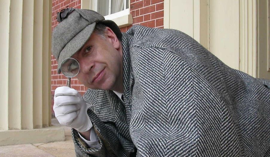 Actor dressed as Sherlock Holmes with Magnifying Glass