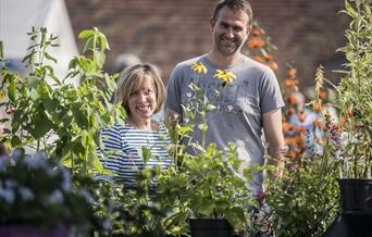 Two people smiling behind some plants