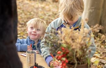 Two young boys doing crafts in the woods