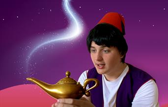 A young boy with black hair and wearing a red fez, Aladdin, holds a golden lamp