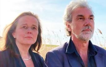 Headshot of a woman and a man standing outdoors looking just off the camera.