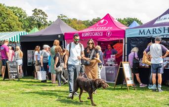 Two people and their dog in front of the food stalls at North Norfolk Food and Drink Festival